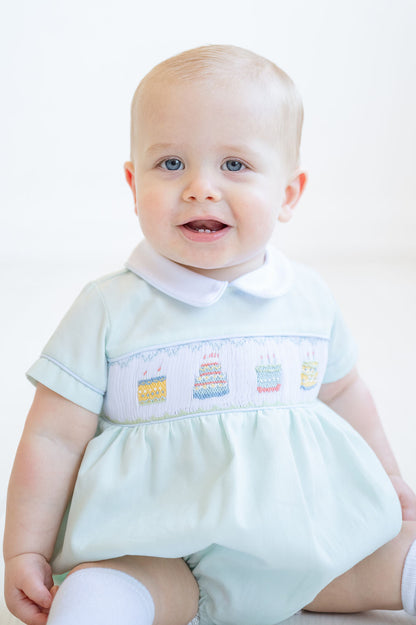 A little boy shines in the smocked mint green birthday cake bubble, the perfect outfit for making birthday memories.