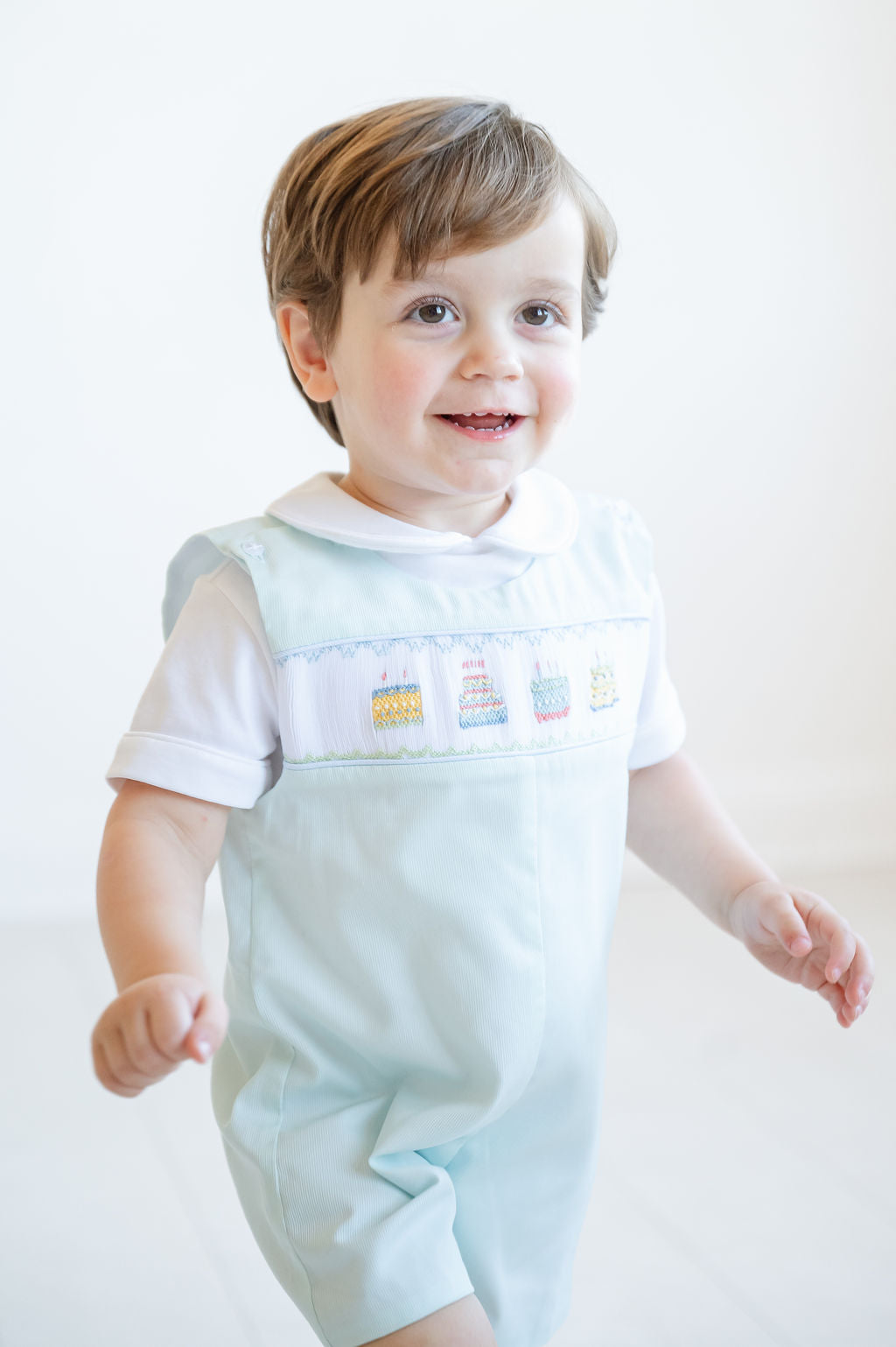 In his smocked mint green jonjon, a little boy shines with timeless style, perfect for photos and sweet moments.