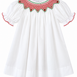 A white cotton dress for toddlers or girls, featuring short puff sleeves with red and green ruffled trim, and a decorative embroidered yoke with a red and green checkered pattern and green border.