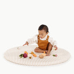 Baby playing with wooden toys on a striped mat