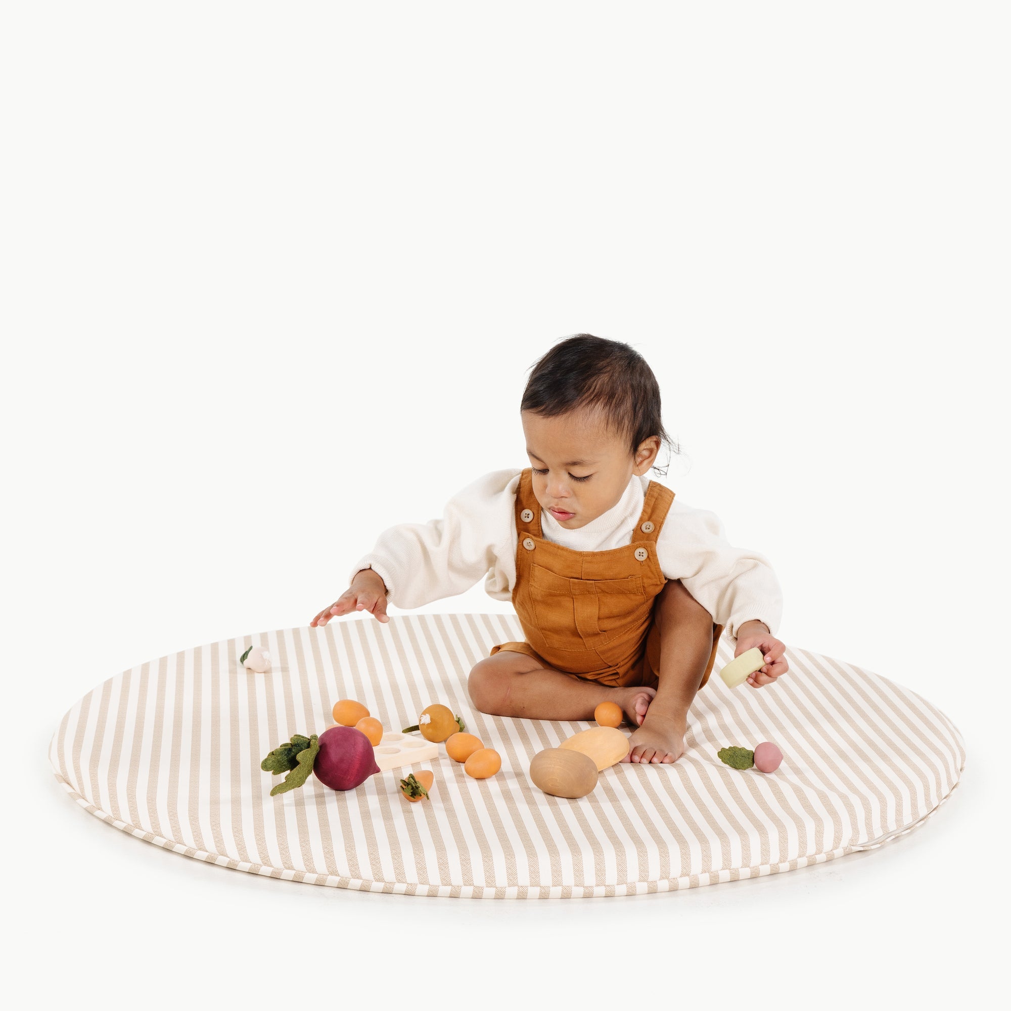 Baby playing with wooden toys on a striped mat