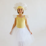 Child in a yellow dress with flower headband and white skirt on a plain background