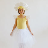 Child in a yellow dress with flower headband and white skirt on a plain background