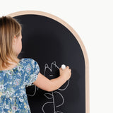 Child drawing on a round blackboard with a white marker.