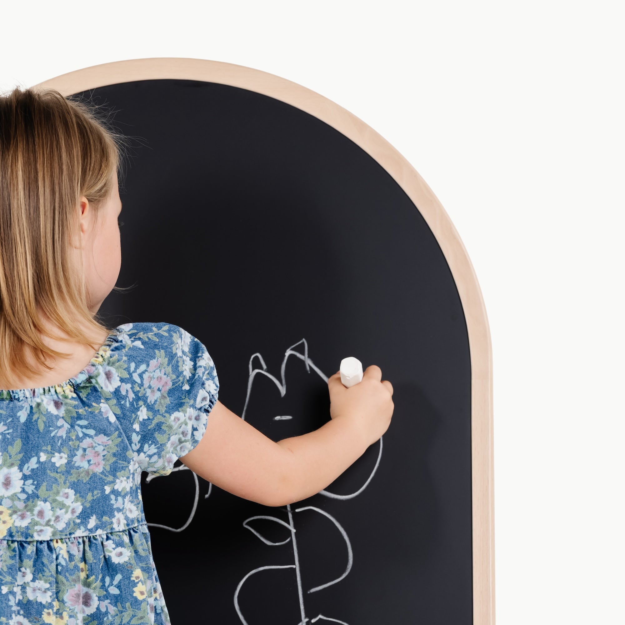 Child drawing on a round blackboard with a white marker.