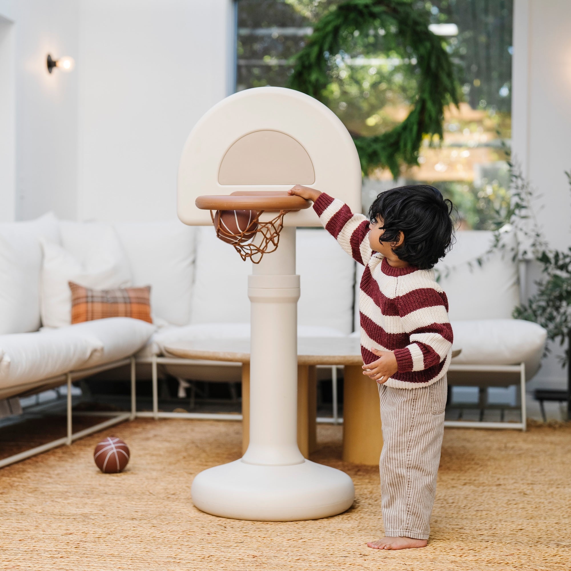 Child playing with a basketball hoop in a living room.