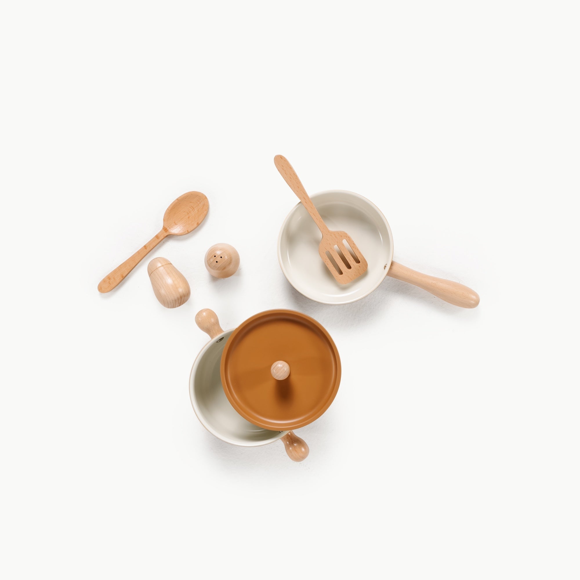 Set of ceramic cookware with wooden utensils on a white background