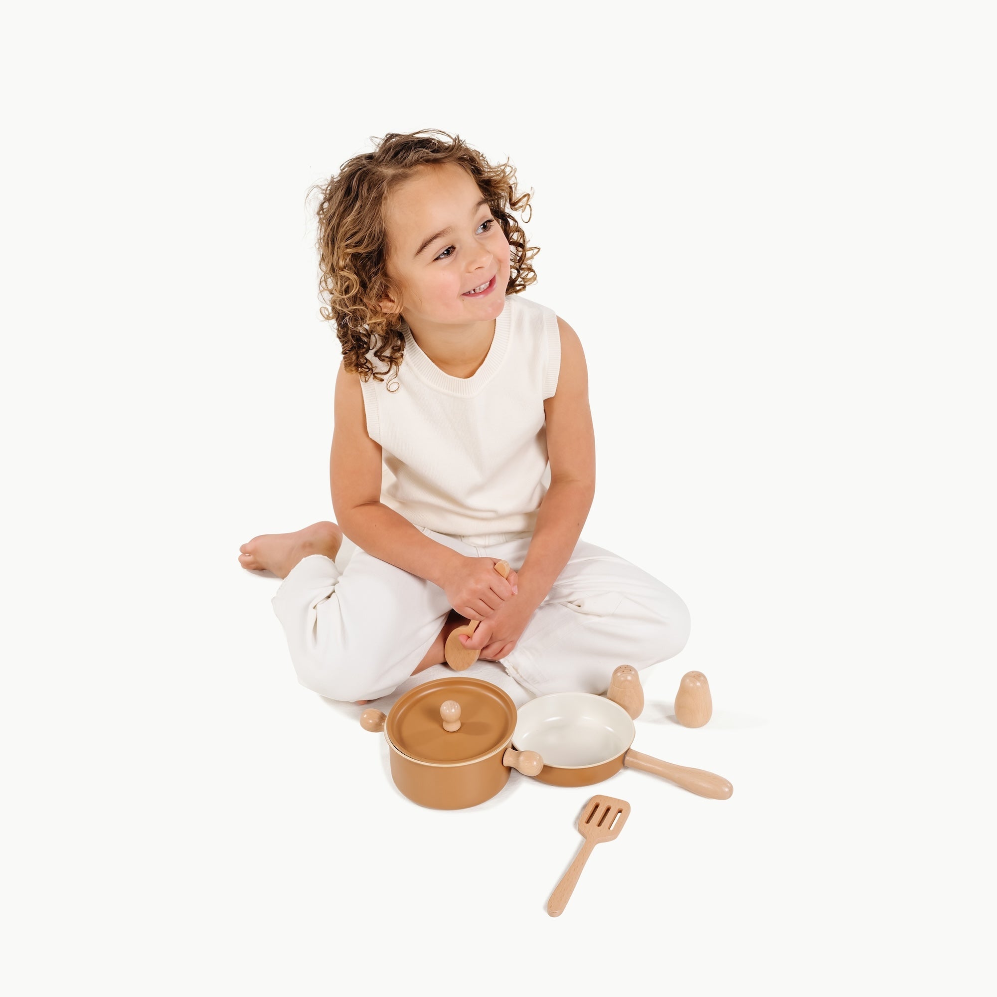 Child playing with wooden kitchen toys on a white background
