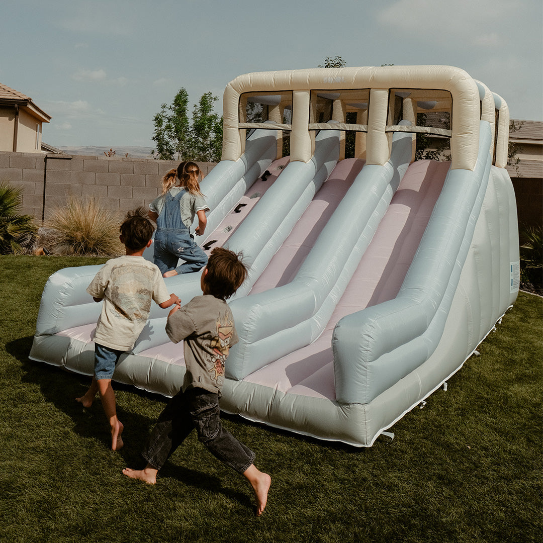 Children playing with an inflatable slide in a backyard