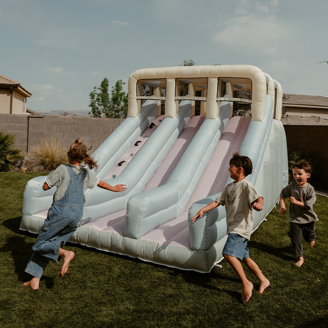 Children playing on an inflatable slide in a backyard.
