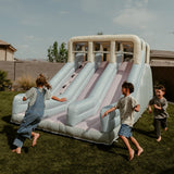Children playing on an inflatable slide in a backyard.
