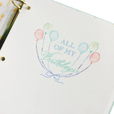 Notebook with decorative cover featuring balloons and text on a white background