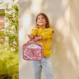 Girl holding a pink glittery lunch bag outdoors