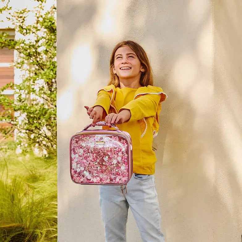 Girl holding a pink glittery lunch bag outdoors