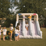 Children playing on an inflatable slide in a park with trees in the background