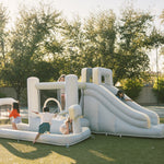 Children playing on an inflatable playground structure in a park.