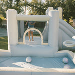 Inflatable bounce house with a slide and ball pit in an outdoor setting