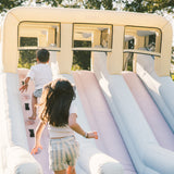 Children playing on an inflatable slide structure outdoors.