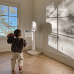 Child playing with a basketball hoop in a room with a large window.