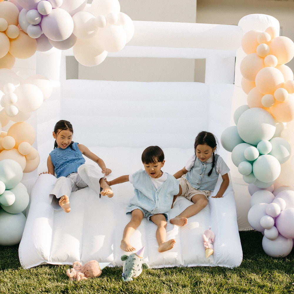 Children sitting on a inflatable chair with balloon arches in the background