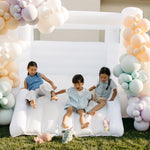 Children sitting on a inflatable chair with balloon arches in the background