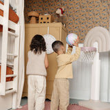 Two children playing with a basketball in a room.