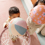 Two children playing with colorful balls on a checkered blanket