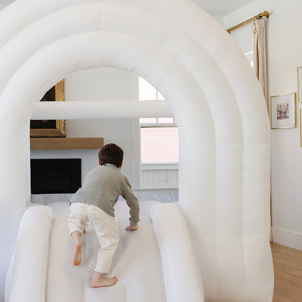 Child playing inside an inflatable tunnel in a living room.