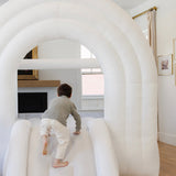 Child playing inside an inflatable tunnel in a living room.