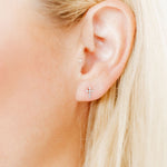 Close-up of a person's ear with earrings against a blurred background