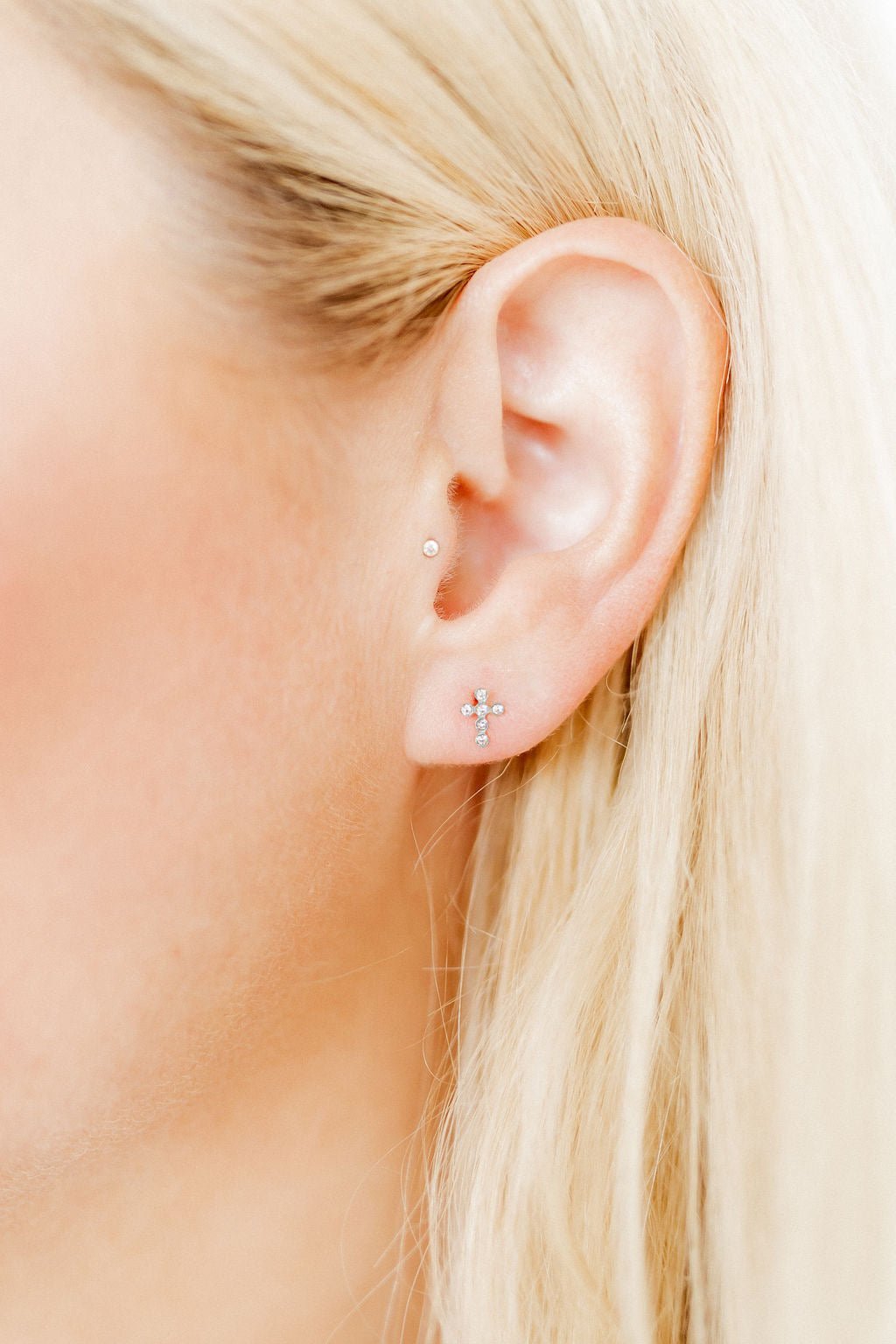 Close-up of a person's ear with earrings against a blurred background