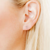 Close-up of a person's ear with earrings against a blurred background