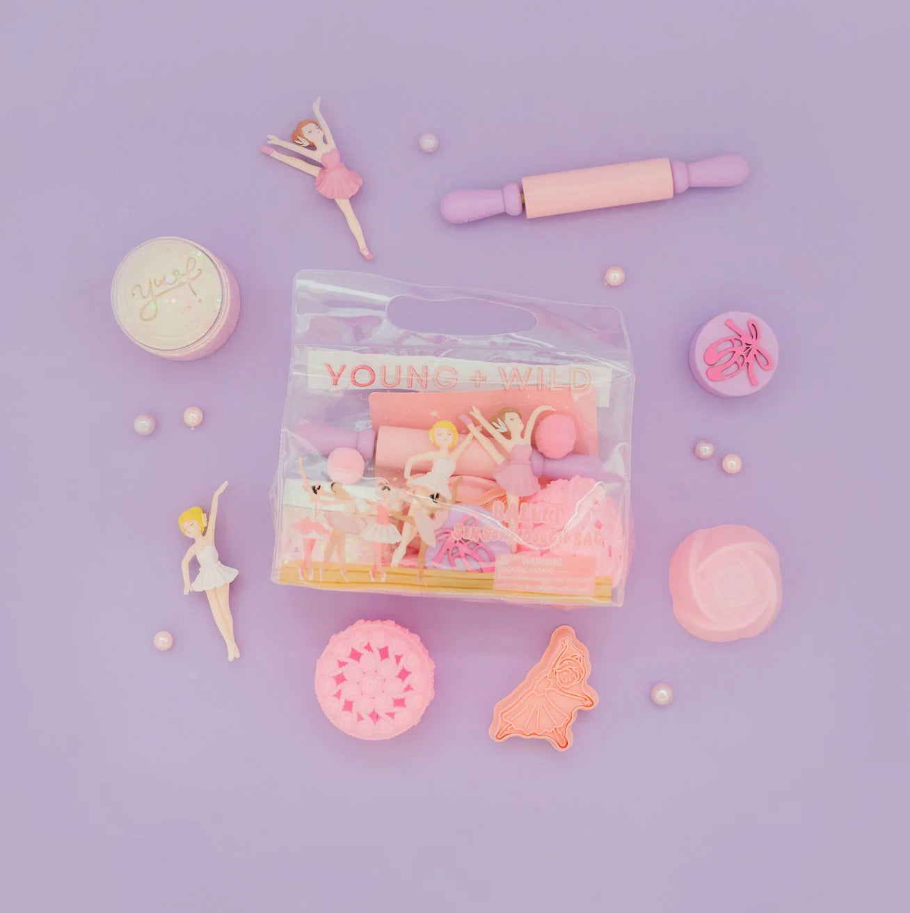 Packaged toy set with ballerina figures and baking tools on a purple background