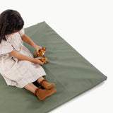 Child playing with a toy on a green mat