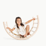 Child sitting on a wooden rocking toy against a white background